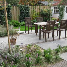 bestrate tuin met houten tafels en stoelen